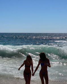 two women in bikinis walking on the beach