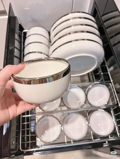 someone is holding a bowl in front of the dishwasher