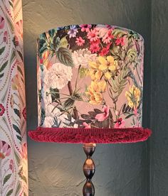 a lamp that is on top of a table with a flowered lampshade