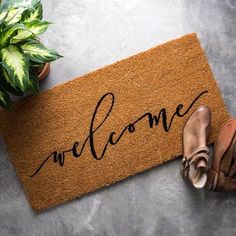 a welcome mat with the word welcome on it and shoes next to potted plant