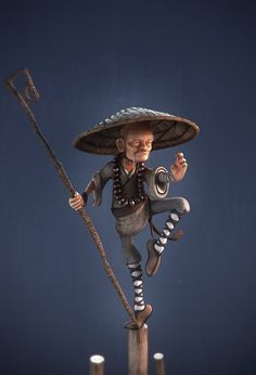 a statue of a man on top of a pole holding a stick and wearing a sombrero