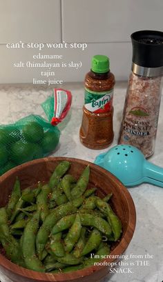 green beans in a wooden bowl with seasoning and salt on the counter next to it