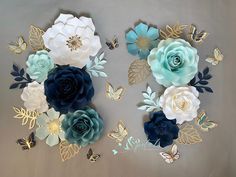 paper flowers and butterflies are arranged on a sheet of white, blue, and gold foil