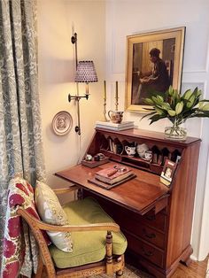 a chair and desk in a room with a painting on the wall behind it, along with a potted plant