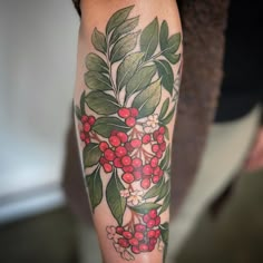 a person with a tattoo on their arm has berries and leaves on the arm,