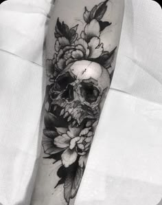 a black and white skull with flowers on its arm