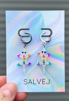 a person holding up a pair of earrings in front of a white card with the word salvej on it