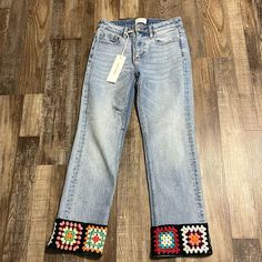 a pair of jeans with colorful beading on the side and an empty tag hanging from the back