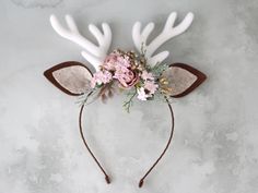 a deer headband with flowers and antlers is shown on a white table top