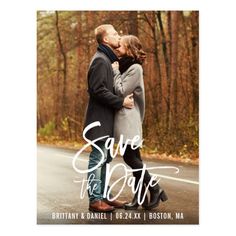 a couple kissing in the middle of an empty road with trees and foliage behind them