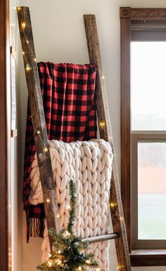 a ladder that is next to a christmas tree in front of a window with lights on it