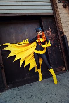 a woman dressed as a batgirl standing in front of a garage door