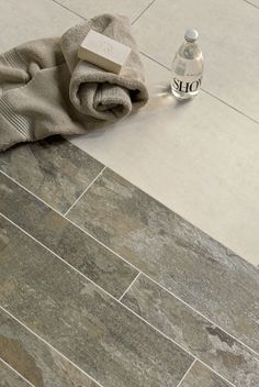 a bottle of water sitting on top of a tile floor next to a towel and cloth