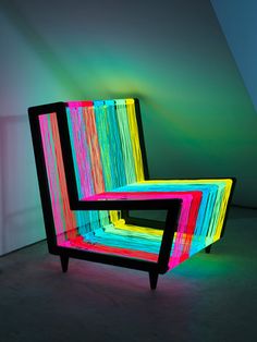 a colorful chair sitting on top of a floor next to a white wall in a room