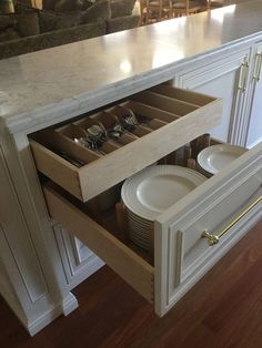 an open drawer in the middle of a kitchen counter with plates and silverware on it