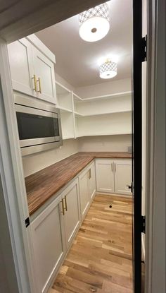 an empty kitchen with white cabinets and wood flooring is seen through the door way