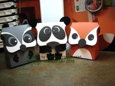 three panda and raccoon papercrafts sitting on a table in an office