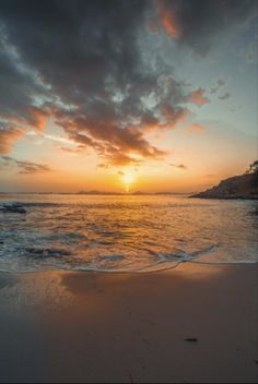 the sun is setting over the water on the beach