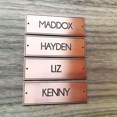 three metal name tags on top of a wooden table