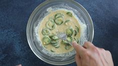 someone is mixing up some food in a glass bowl with a silver utensil