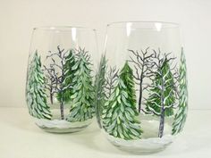 two glasses with trees painted on them sitting next to each other in front of a white background