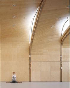 a person sitting on the floor in front of a wall with arches and ceiling lights