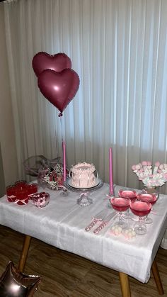 a table topped with cake and balloons on top of a hard wood floored floor