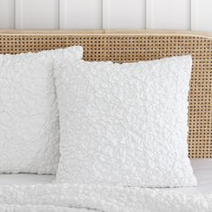 two white pillows sitting on top of a bed next to a headboard with wicker panels