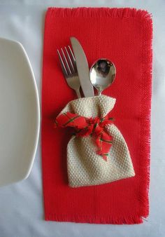 a napkin with a red bow on it next to a fork and spoon in a bag