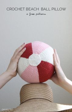 two hands holding up a crocheted beach ball on top of another person's head