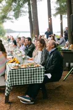 a group of people sitting around a table with food in front of them on picnic tables