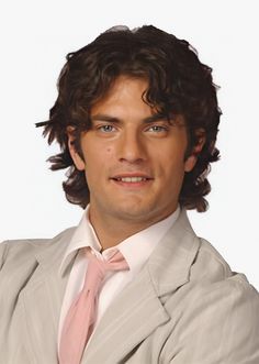 a man in a suit and pink tie posing for a photo with his arms crossed