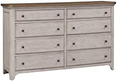 a white dresser with brown top and drawers on the bottom drawer, against a white background