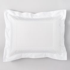 a white square pillow on a gray wall with a black and white photo frame in the middle