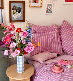 a vase filled with colorful flowers sitting on top of a table next to a bed