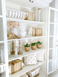 a white book shelf filled with lots of books and vases on top of it