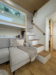 a living room filled with furniture next to a stair case and wooden floored walls