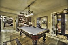 a pool table in the middle of a living room with lots of shelves and chairs