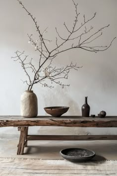 a wooden table topped with a vase filled with flowers next to a bowl and plate