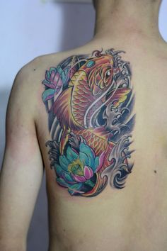 a man with a tattoo on his back has a koi fish and lotus flowers