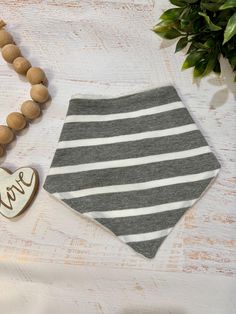 a gray and white striped bandana next to a wooden bead necklace on a table