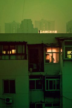 an apartment building with the city lights on in the background at night, and foggy skies