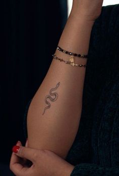 a woman's arm with a snake tattoo on it and a beaded bracelet