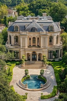 an aerial view of a large mansion with a pool in the front yard and trees surrounding it