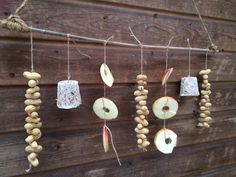 apples and nuts are hanging on a wooden wall next to some string that is attached to the side of a building