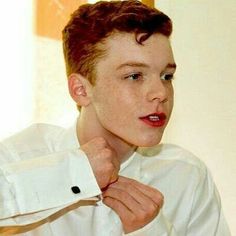 a young man adjusting his white shirt in front of a mirror