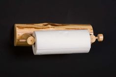 a roll of toilet paper hanging from a wooden holder on a black wall with wood handles