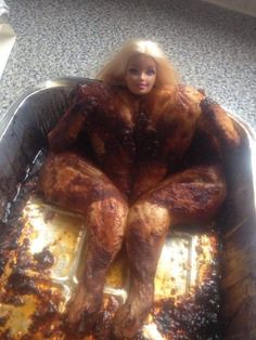 a doll is sitting in a roasting pan with meat on the bottom and sides