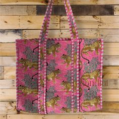 a pink bag with leopards on it hanging from a wooden wall in front of a wood paneled wall