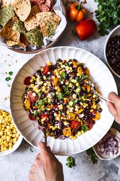 a bowl filled with black beans and corn next to other bowls of food on a table